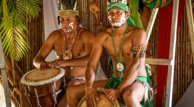 Kalinago people in traditional ceremonial dress playing drums at the Kalinago Barana Autê