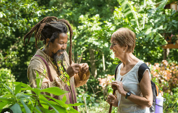 Local Jamaican guide sharing knowledge with a traveler in a lush tropical garden