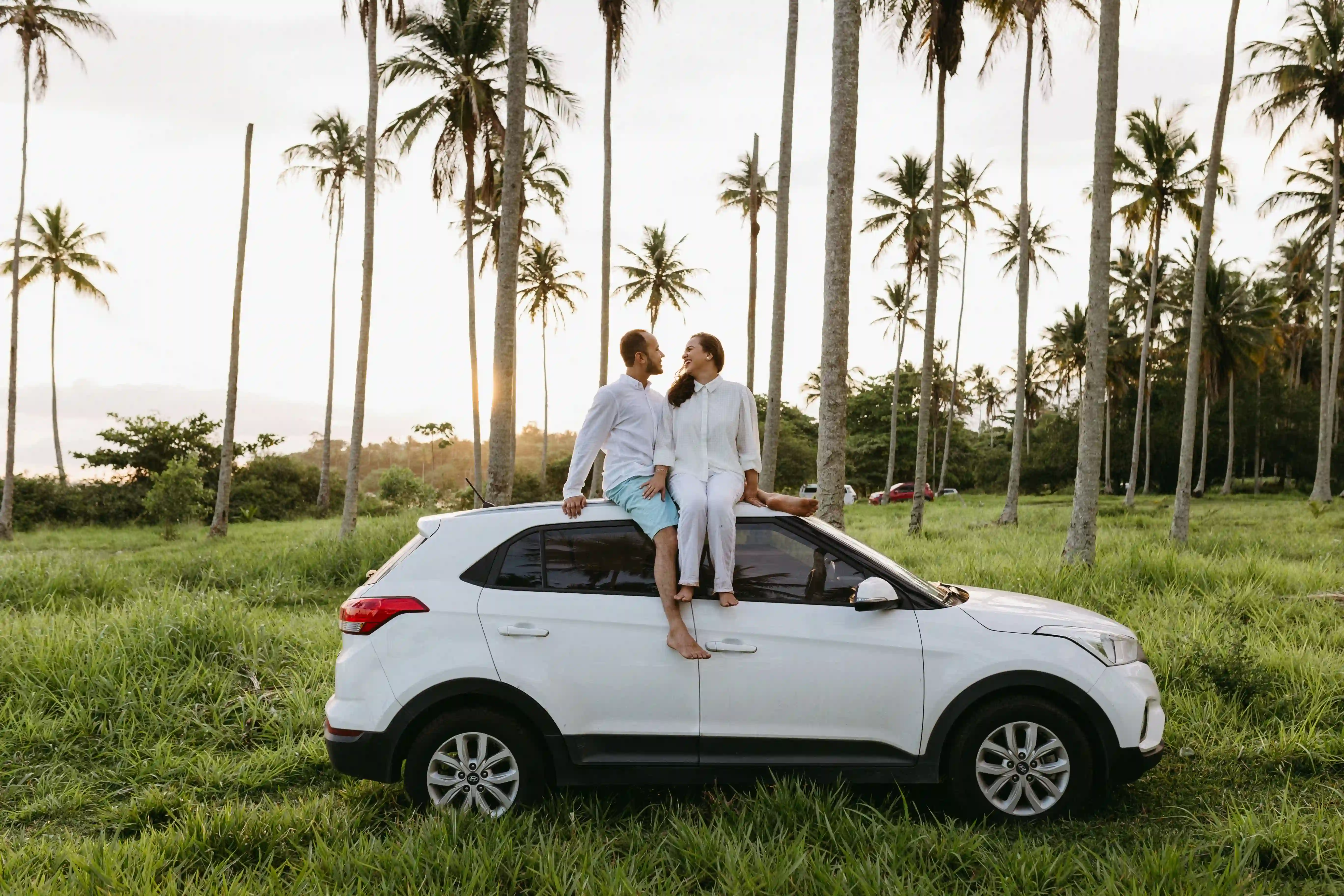 Travelers relaxing on their rental vehicle beneath palm trees in the Caribbean